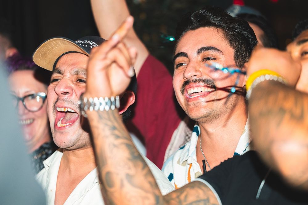 People celebrating at a party with face paint and drinks in a dimly lit venue.