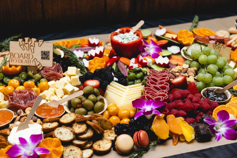 Beautifully arranged charcuterie board with cheese, fruits, nuts and edible flowers.
