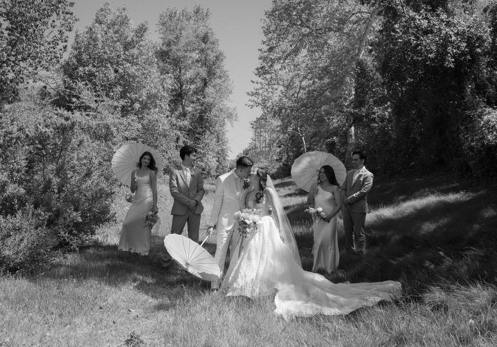 Black and white photograph showing people in vintage formal attire outdoors in a wooded setting in the 1800s.