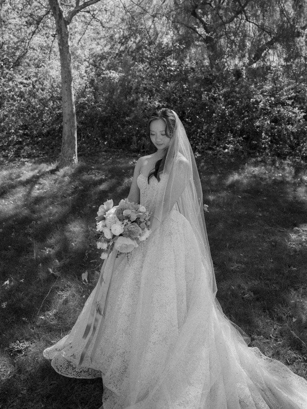 Black and white wedding photos showing flowing white dress details in a garden setting.