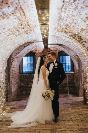 Elegant wedding couple poses for romantic photos in a rustic brick cellar with arched ceilings and soft lighting at Hirst Priory.