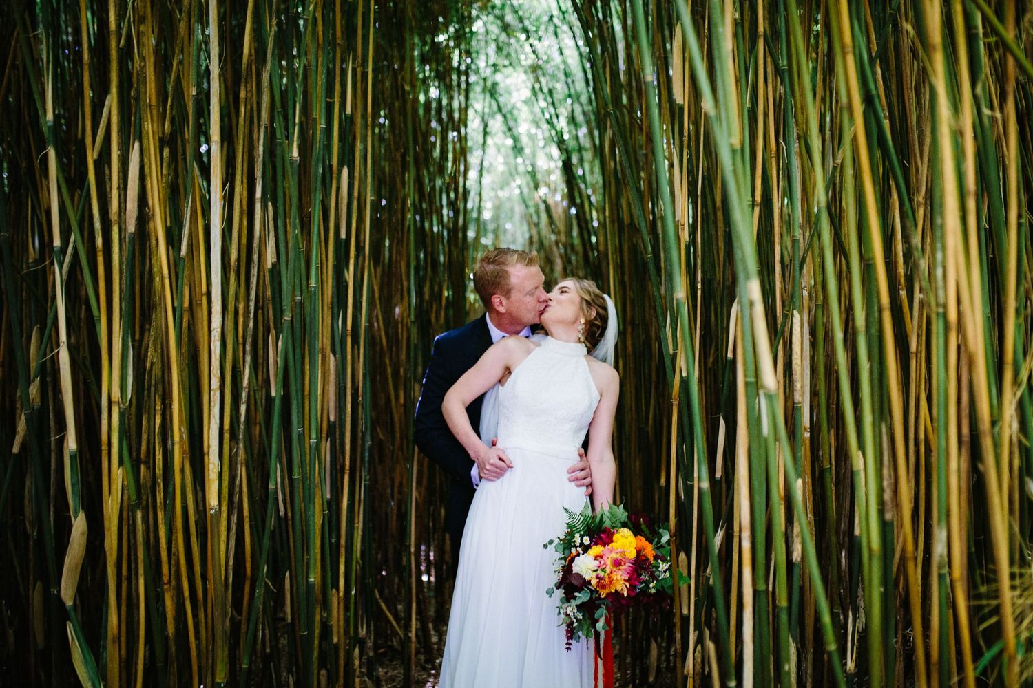 Couple shares romantic moment together surrounded by tall green bamboo forest in natural outdoor setting.