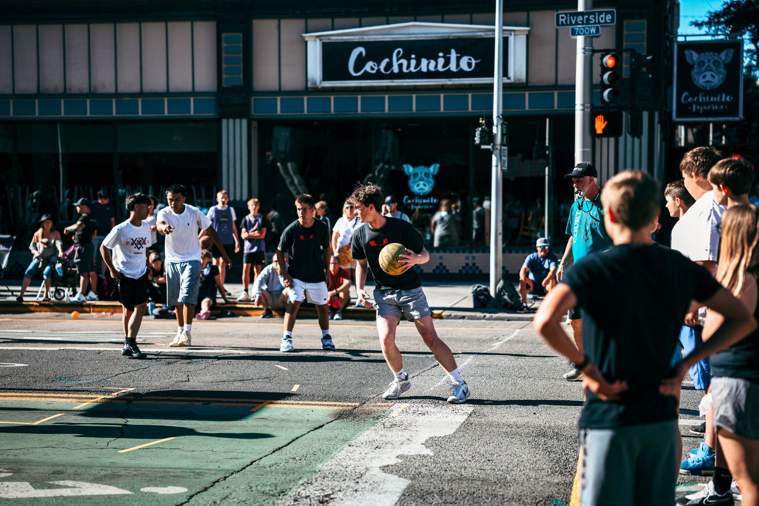 A group of runners racing through a city street intersection with a Carhartt store visible in the background.