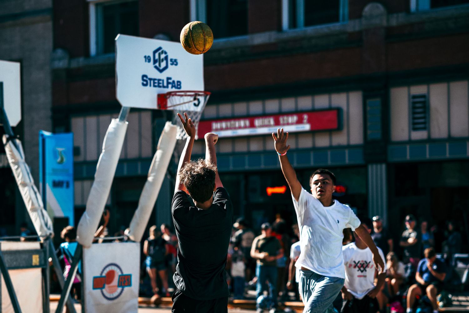 A basketball player in white jersey jumps high to make a slam dunk during an indoor game.