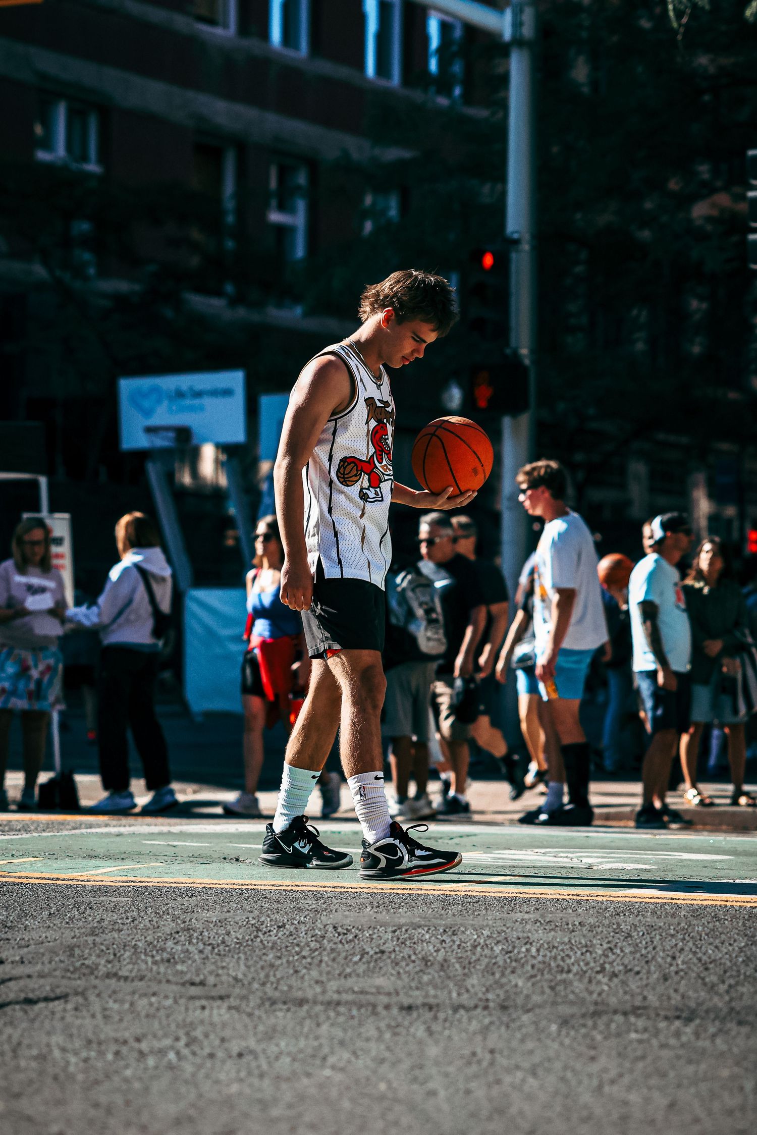 People playing basketball on an outdoor court in an urban setting during a sunny day.