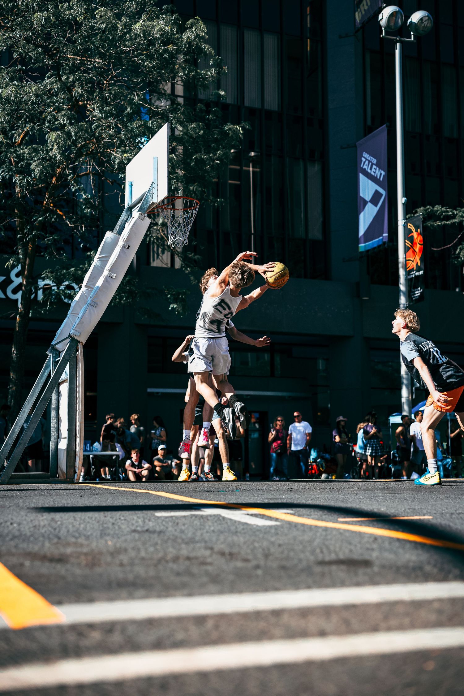 A sequence of skateboarding trick attempts shown in three progressive frames on a sunny urban street.