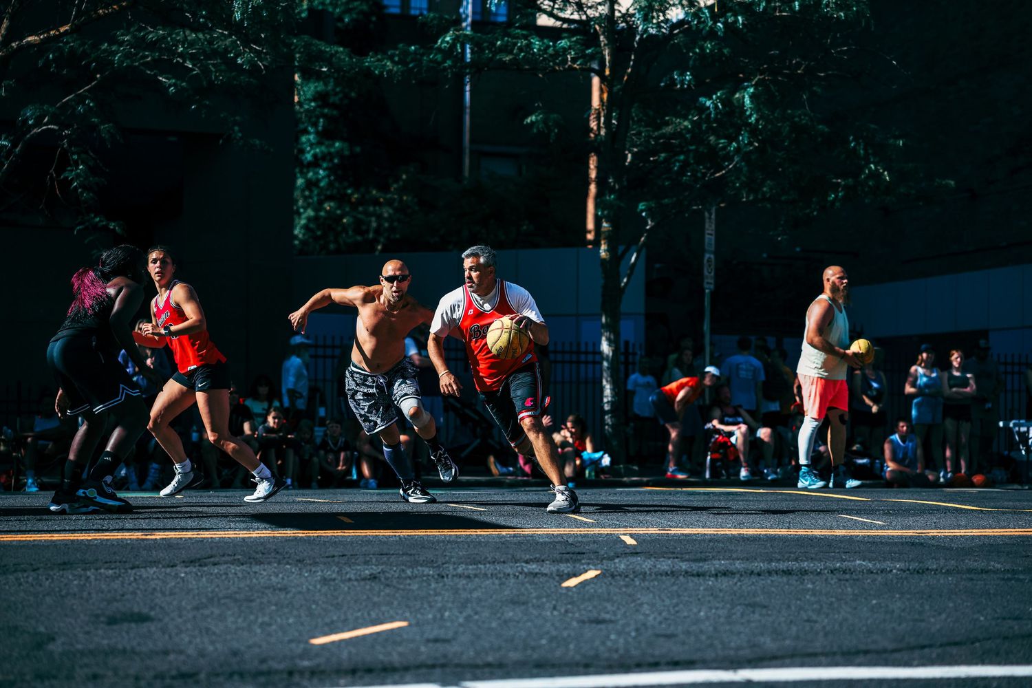 Athletes stretch and warm up together on a paved outdoor surface before a fitness activity.
