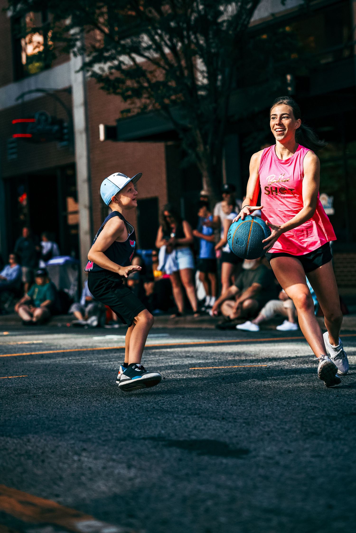 Athletes in pink jerseys playing basketball in an urban environment.