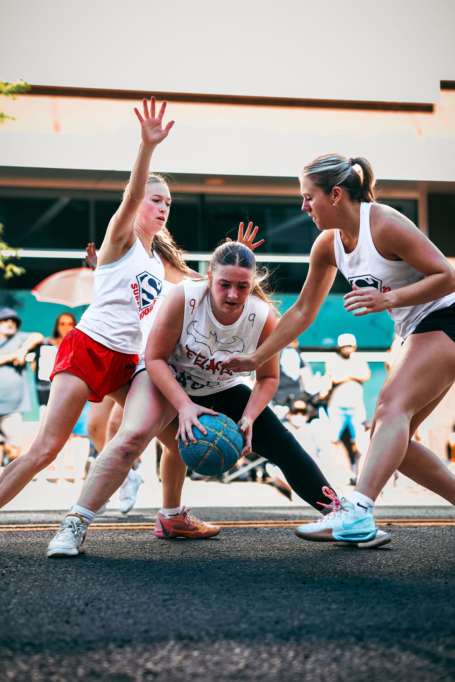Players compete intensely for possession of a blue basketball during an outdoor street game.
