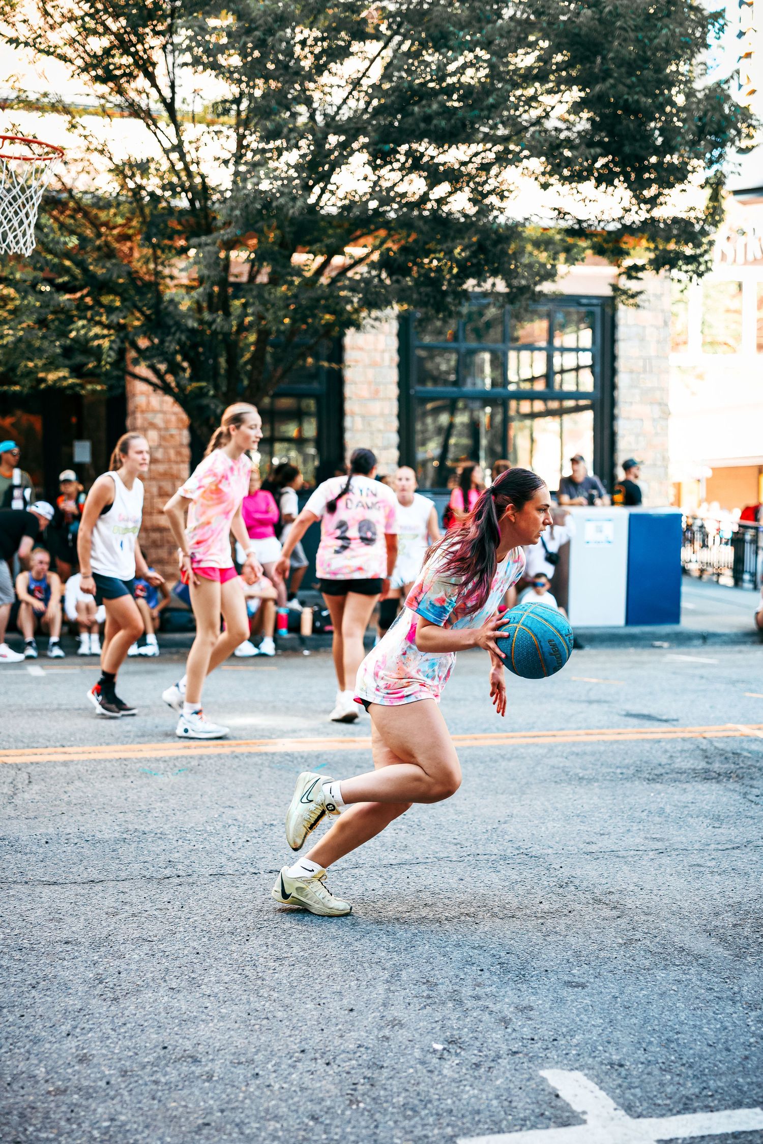 A sequence of photos showing an athlete playing basketball outdoors in an urban environment.