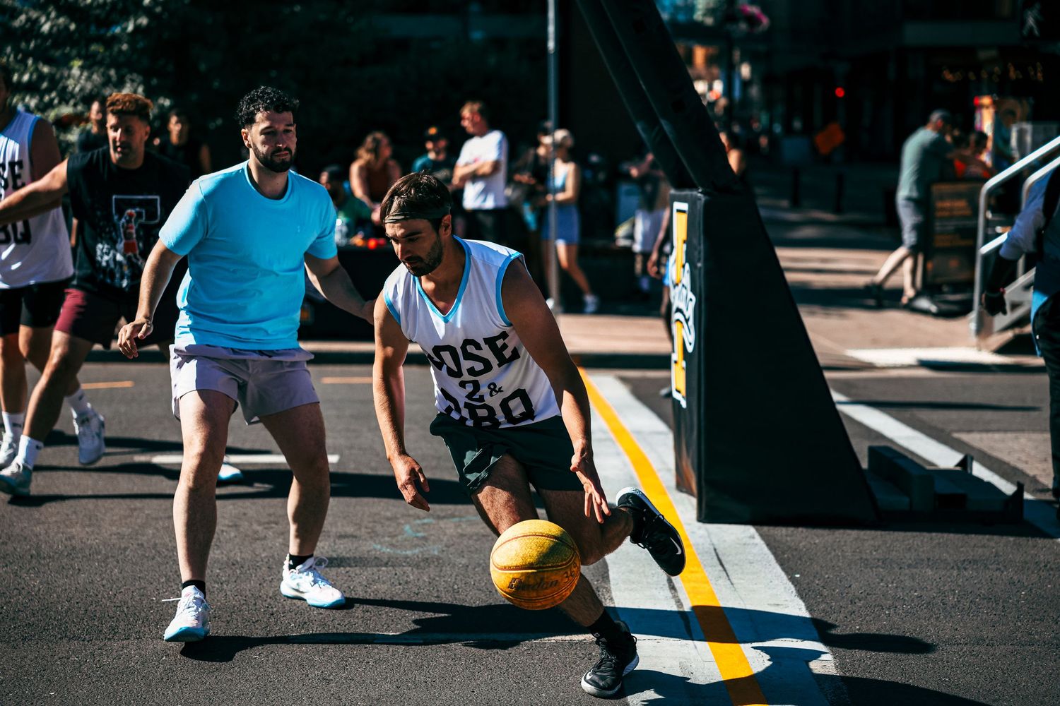 Aerial view of a basketball game in progress on an outdoor court with players in action during daytime.