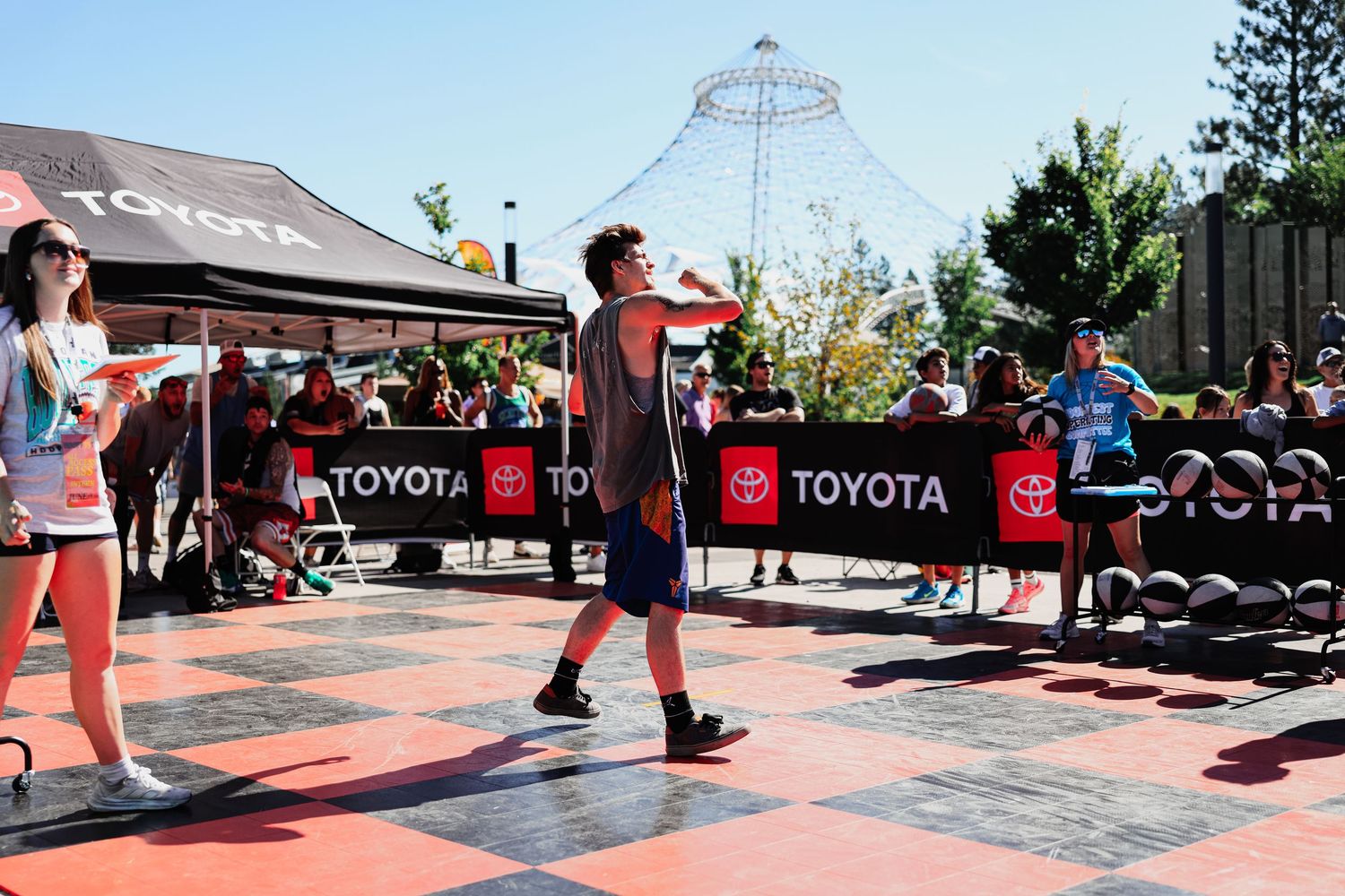 Athletes compete in a CrossFit-style workout competition on a red outdoor platform surrounded by spectators.