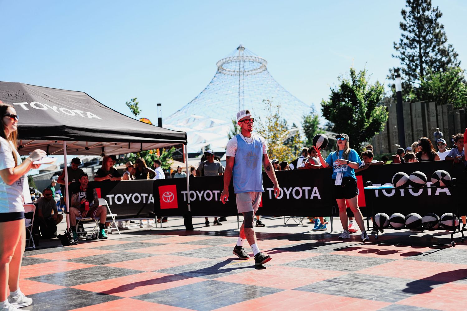 Panoramic view of a crowded outdoor event with Toyota banners and vendor booths set up under sunny skies.