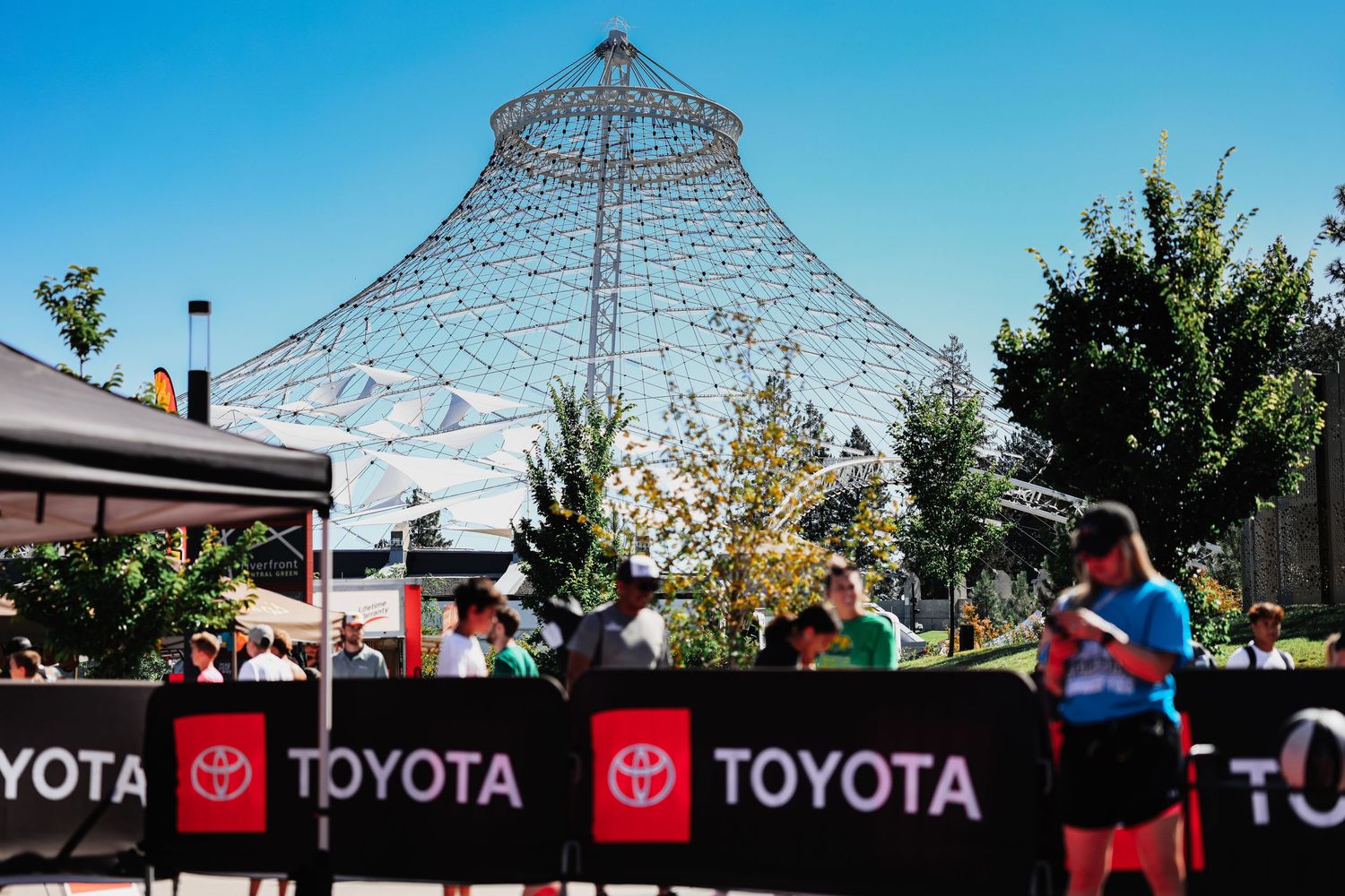Wire frame dome structure against blue sky with Toyota signage and trees visible in outdoor event setting.