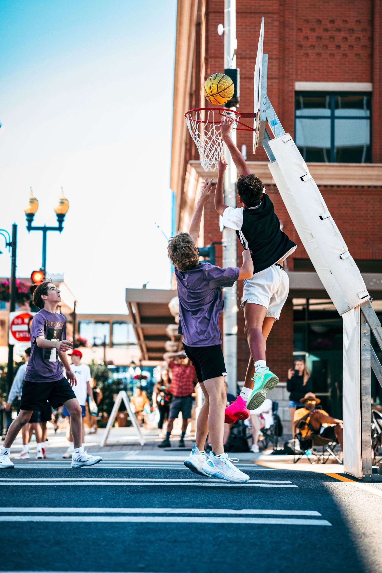 Basketball players leap and reach for the hoop in a dynamic sequence of street basketball action shots.