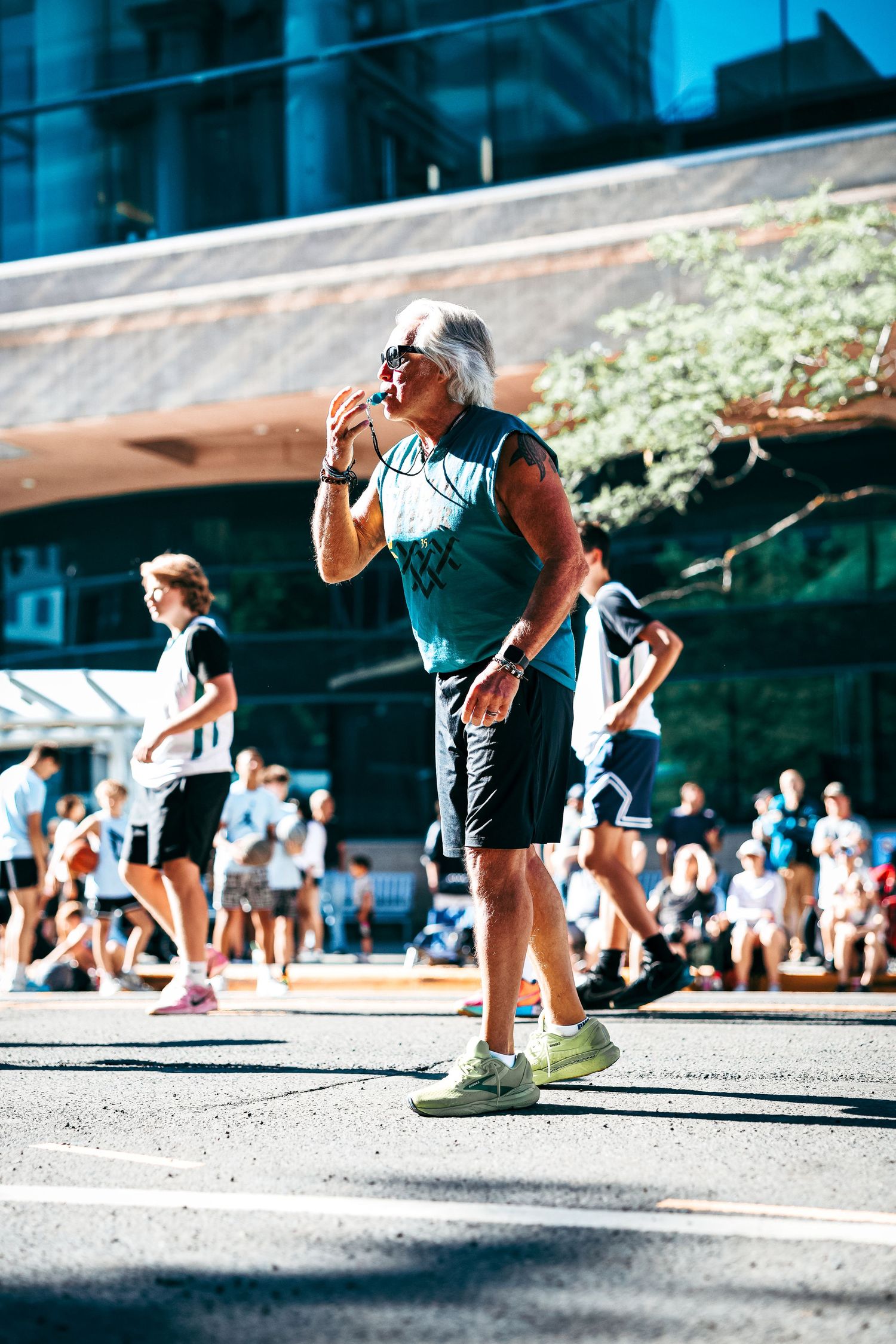 Athletes perform burpee exercises during an outdoor CrossFit workout session in bright sunlight.