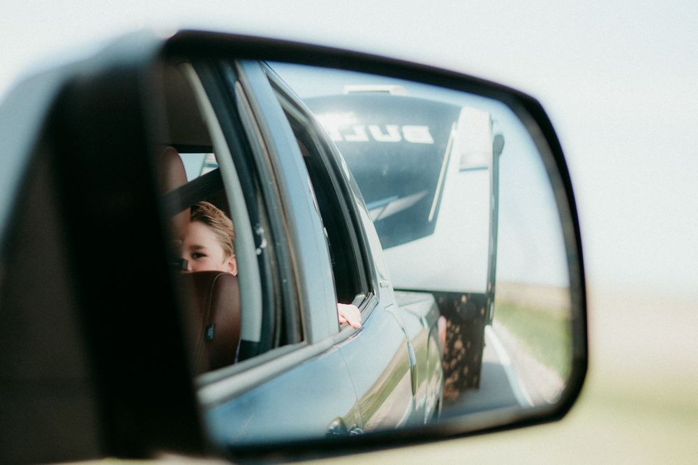 Multiple views through car windows and mirrors show glimpses of a scenic countryside drive on a sunny day.