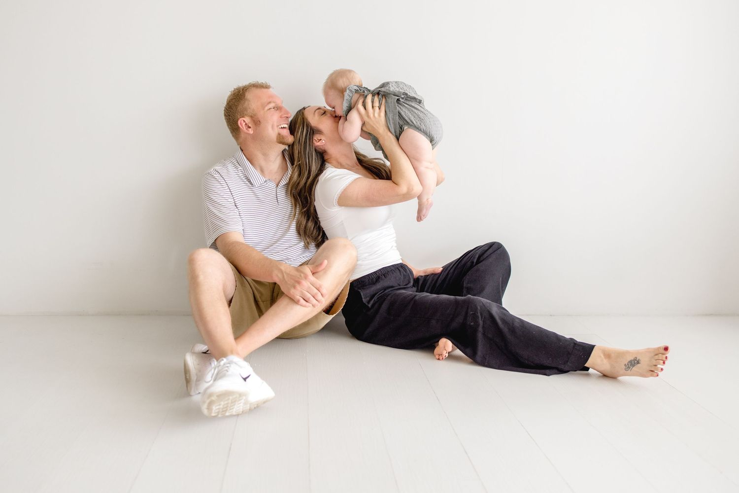 A tender family moment captured in a minimalist white studio setting.