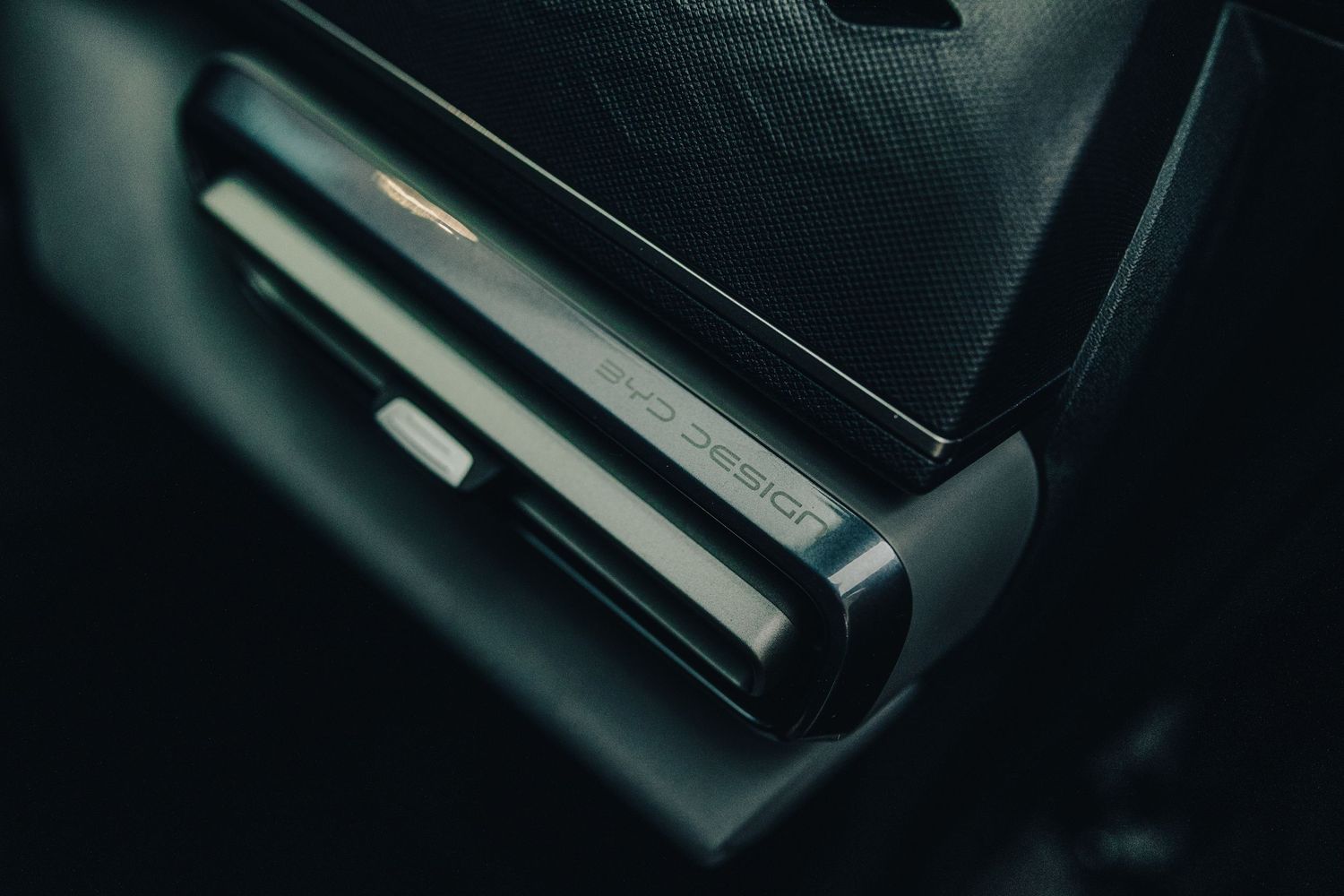 Close-up view of a BYD Dolphin Surf  rear LED light bar and badge in dramatic lighting.