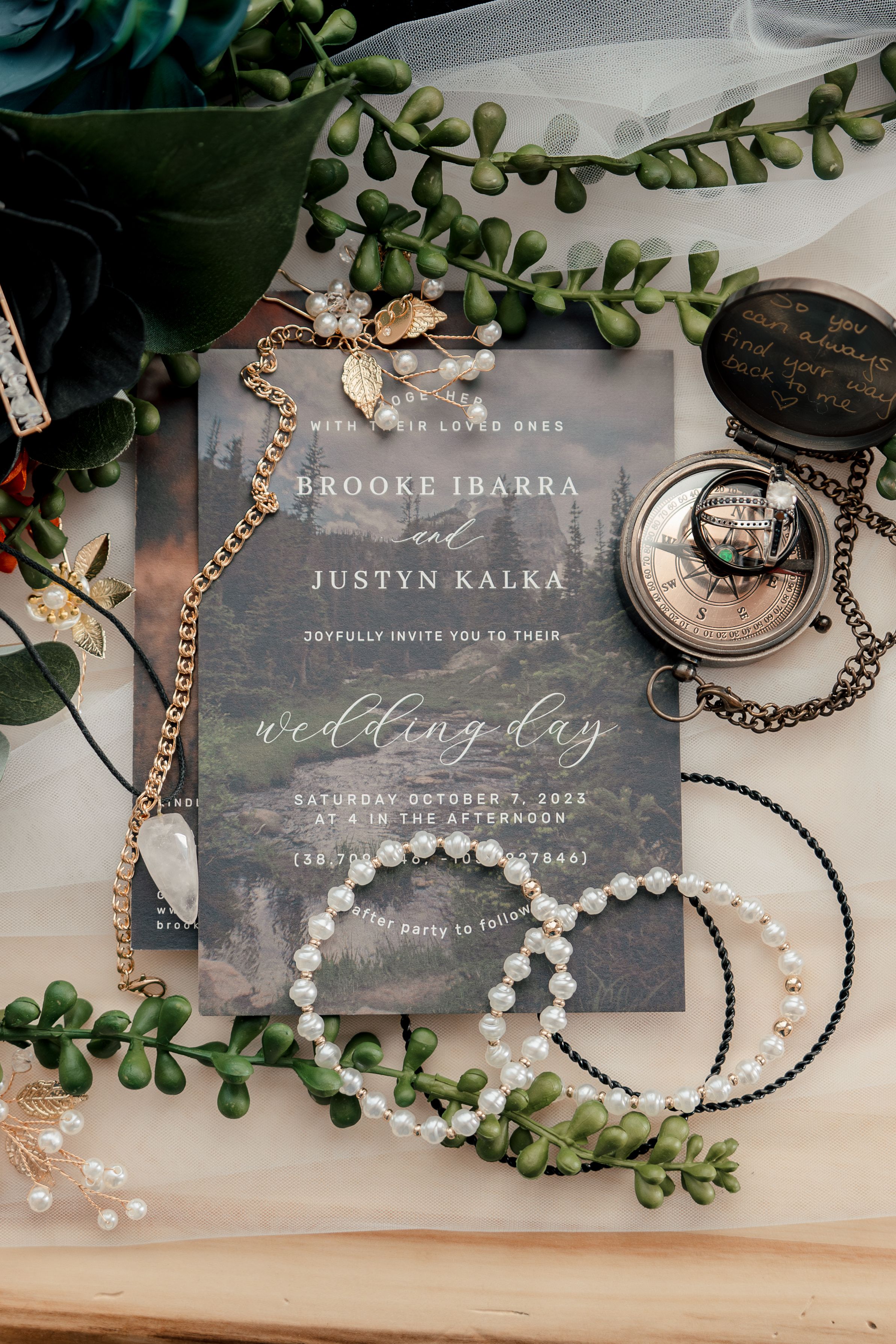 Romantic wedding invitation cards with translucent design styled with pearl jewelry and eucalyptus leaves on wooden surface.