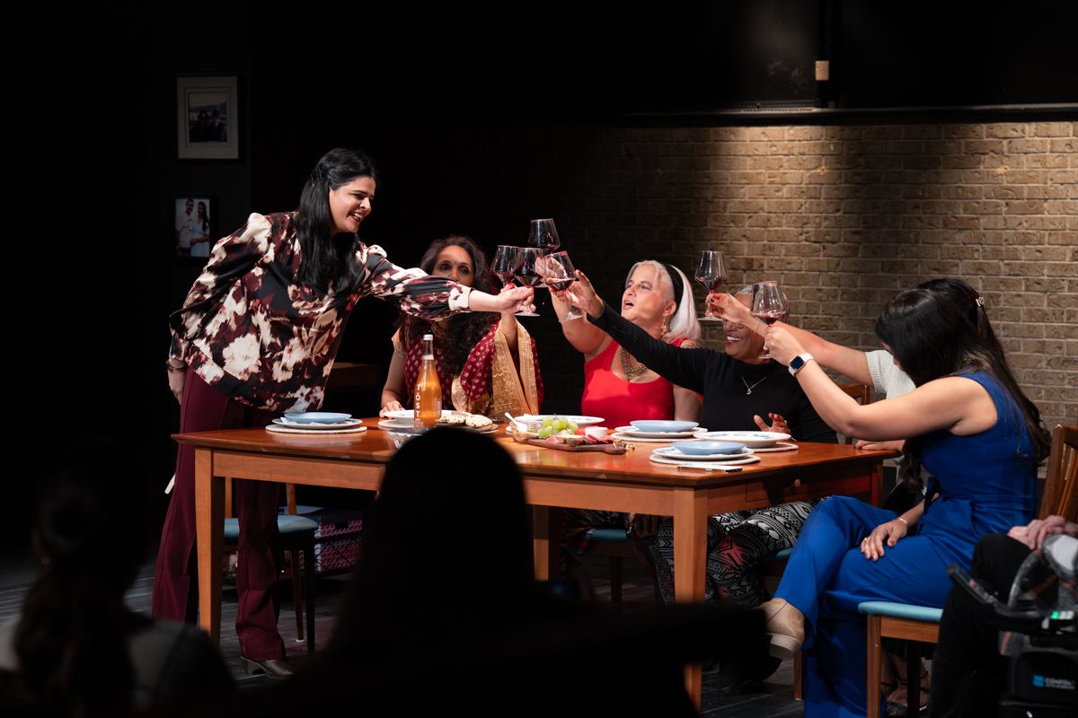 A group of people sitting at wooden tables in a dimly lit restaurant with exposed brick walls.