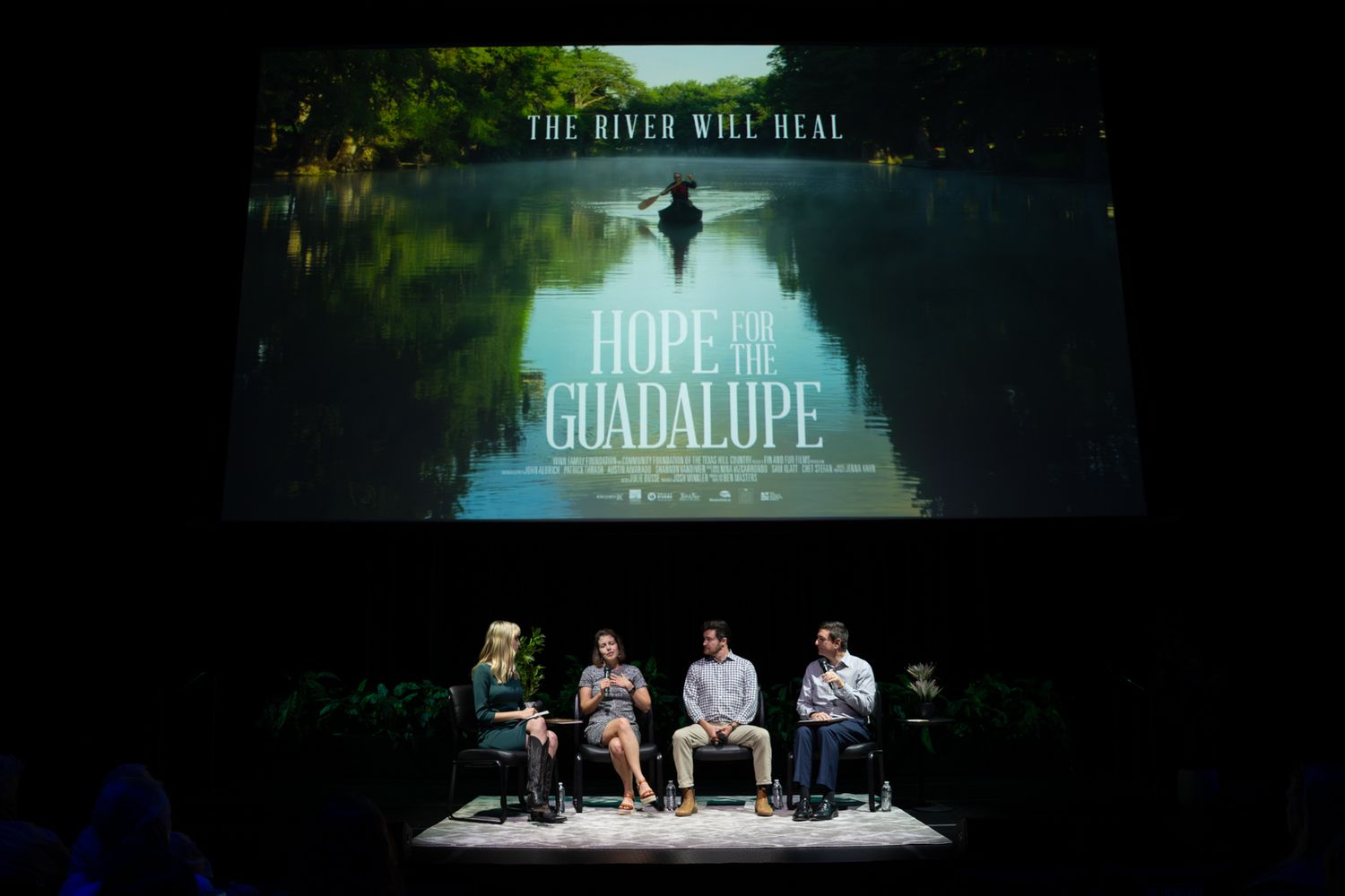Panel discussion at Hope and Guadalupe documentary screening with four speakers seated on stage beneath film poster.