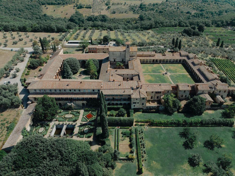 Aerial view of a grand Italian villa with manicured gardens, courtyards and symmetrical architecture.