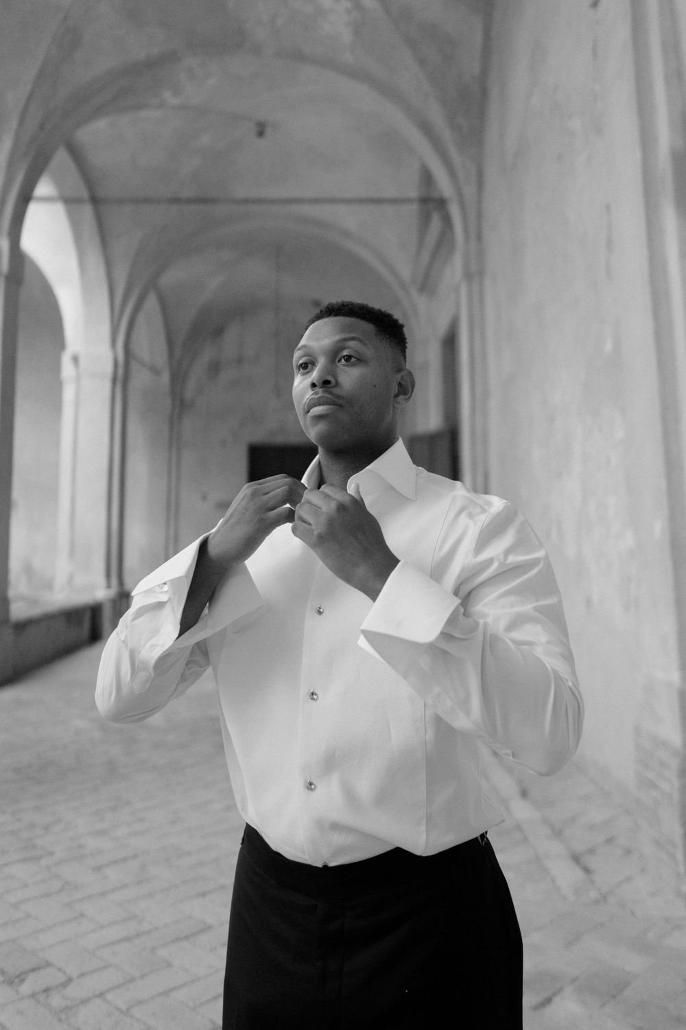 Artistic black and white portrait in an elegant arched hallway.