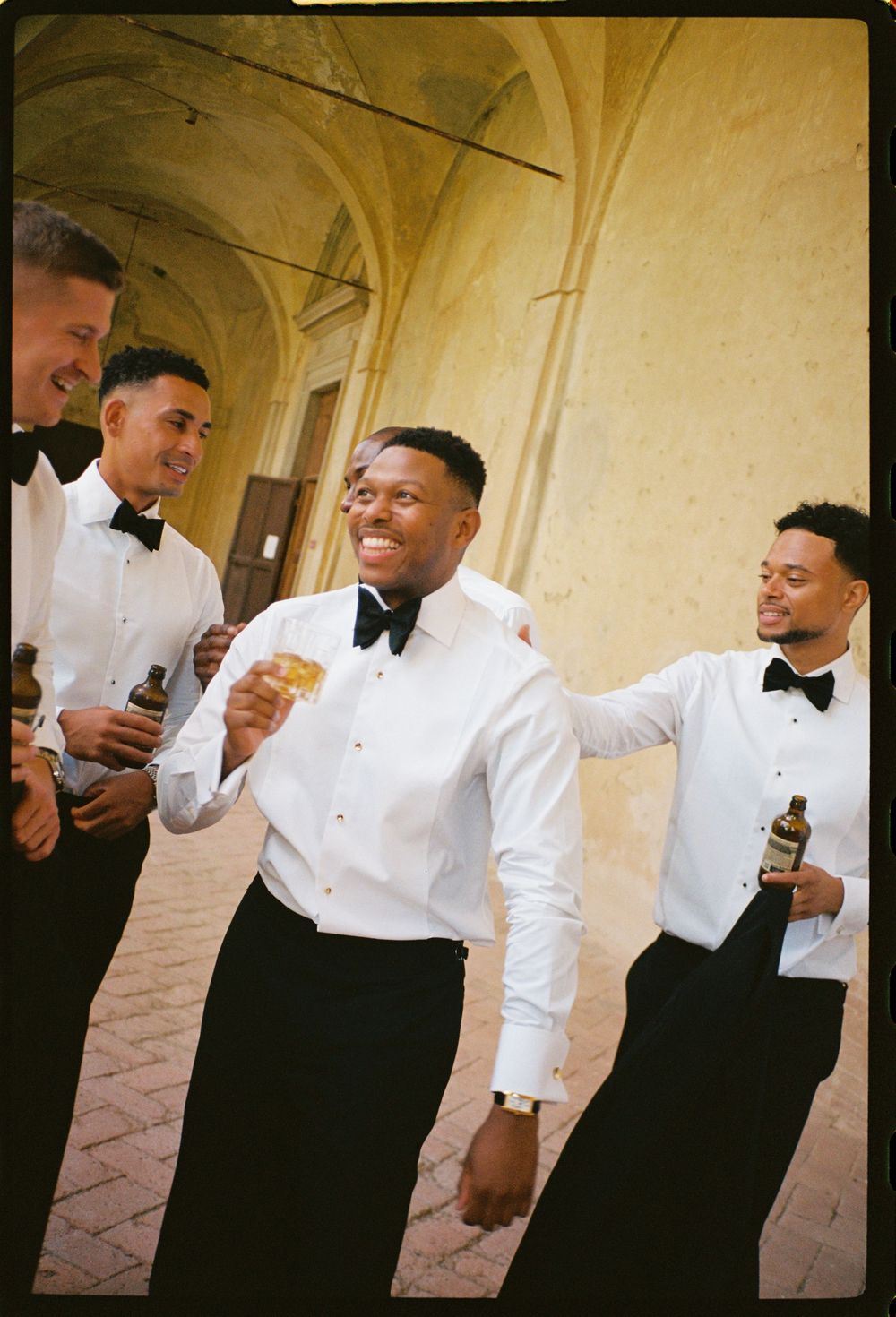 Candid moment of celebration with formal-dressed guests in an elegant corridor.
