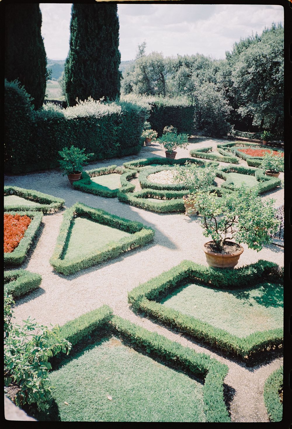 Geometric garden with manicured hedges and pathways forming a symmetrical pattern viewed from above.