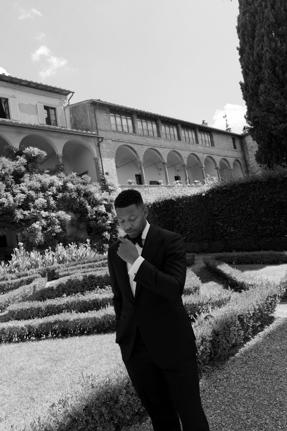A formal garden with arched architecture and hedges in black and white photography.