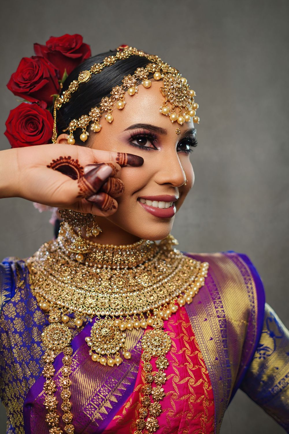 Close-up of intricate gold bridal jewelry with purple and pink traditional attire.