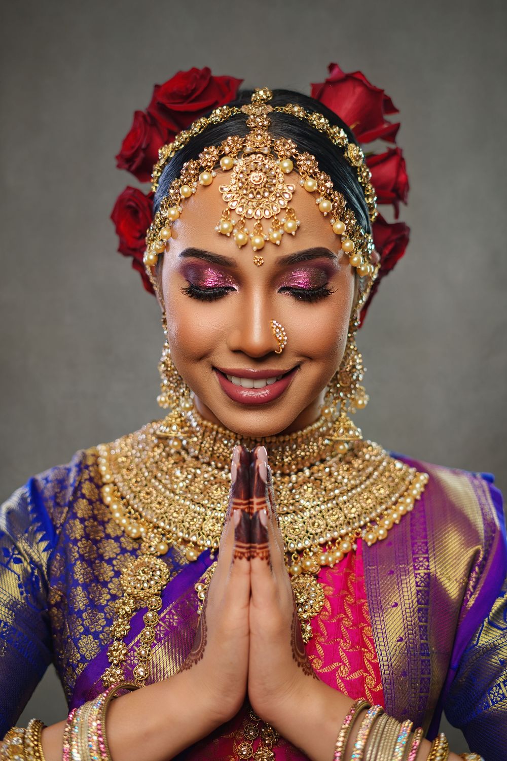 Traditional Indian bridal jewelry and makeup with red roses and ornate gold headpiece in a portrait style series.