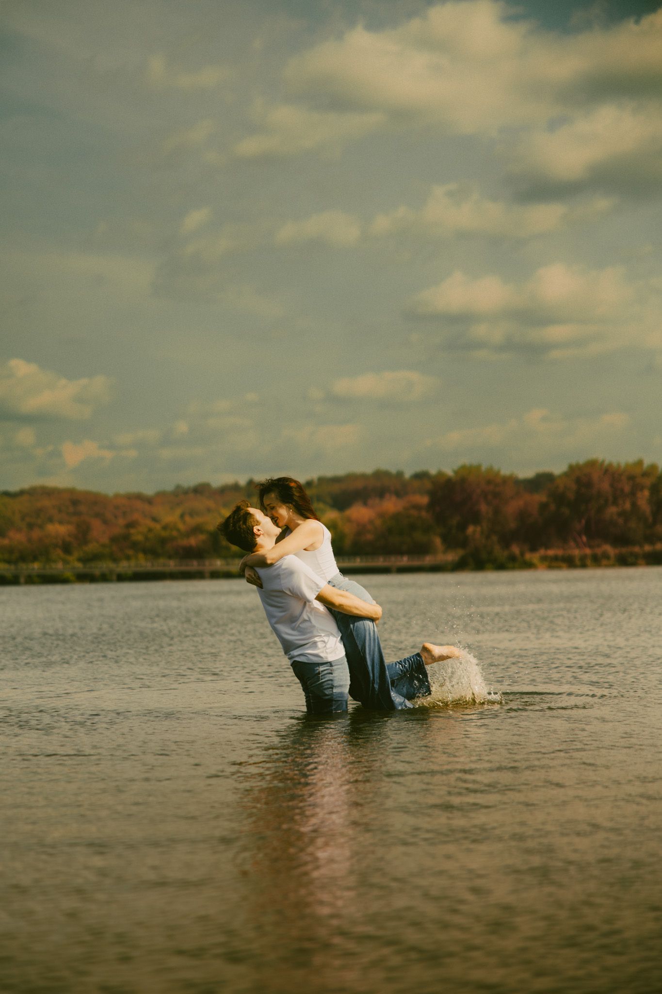 A romantic couple embraces in the shadows of a stone archway with dramatic lighting creating an intimate atmosphere.