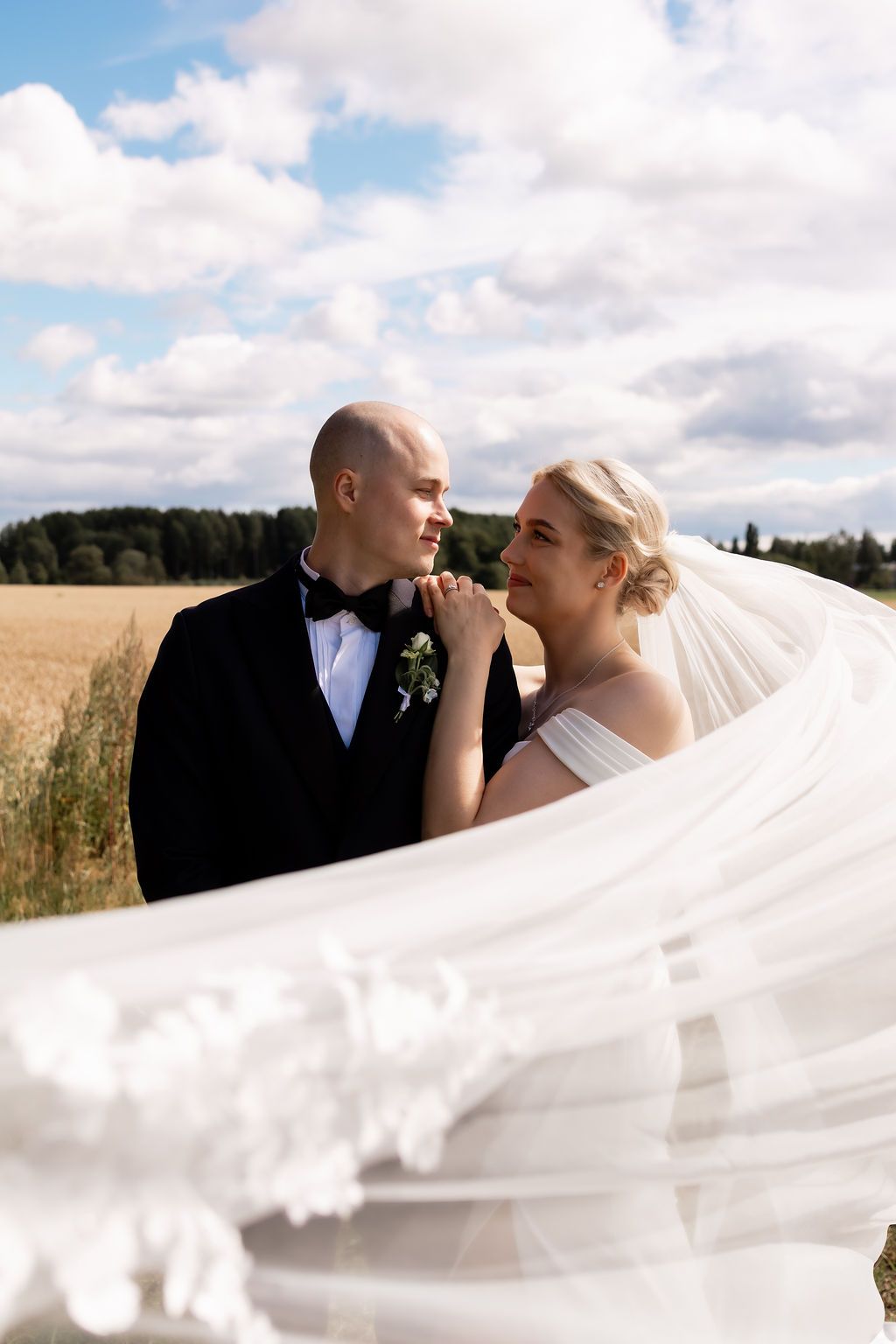 Nuori hääpari, pellolla, sylikkäin, romanttinen, hääkuvaus Muurame, huntu liehuu
