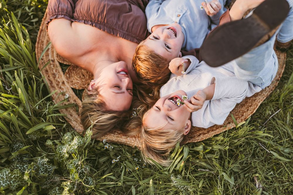 A couple lying in green grass together on a sunny day, photographed from multiple angles.