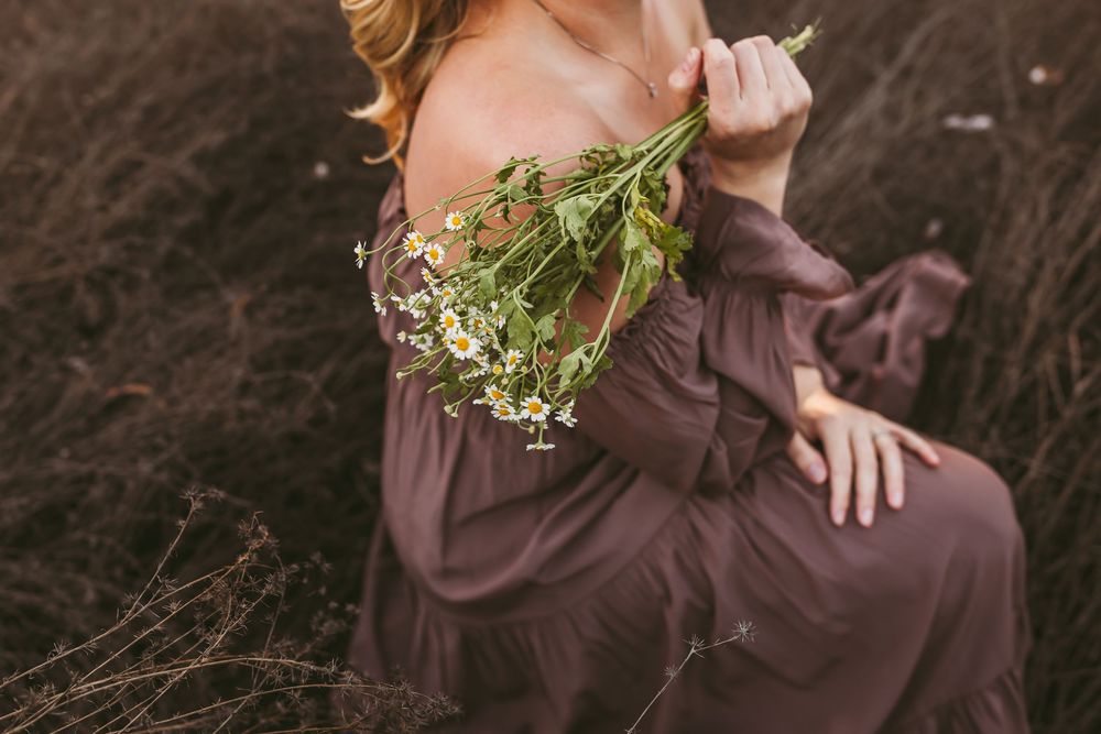 A group of bridesmaids in brown dresses holding delicate white floral bouquets pose together outdoors.