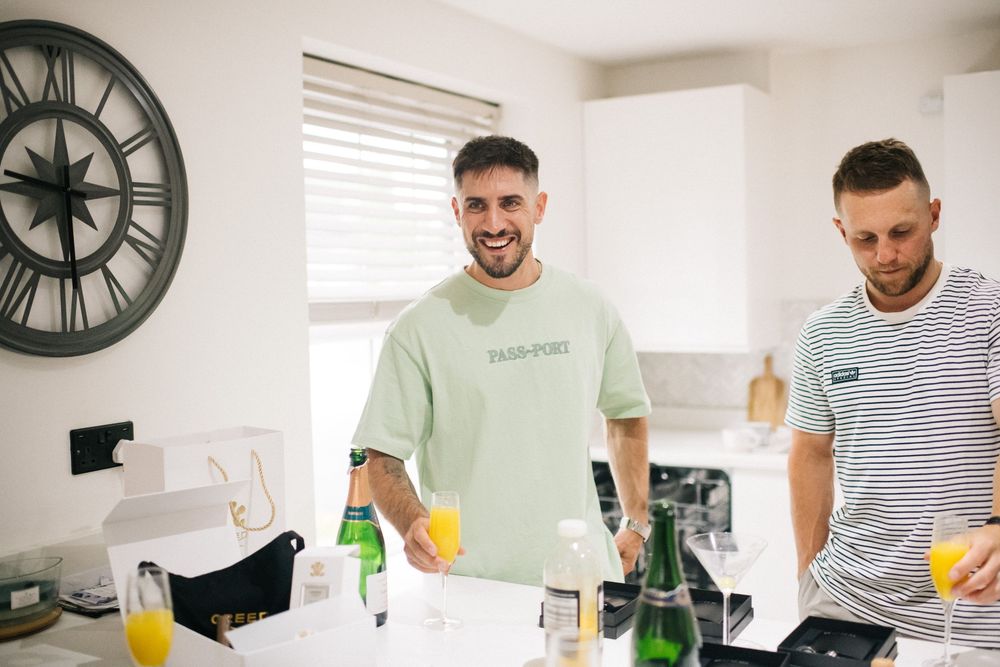 Two people in casual attire preparing drinks in a modern kitchen setting.