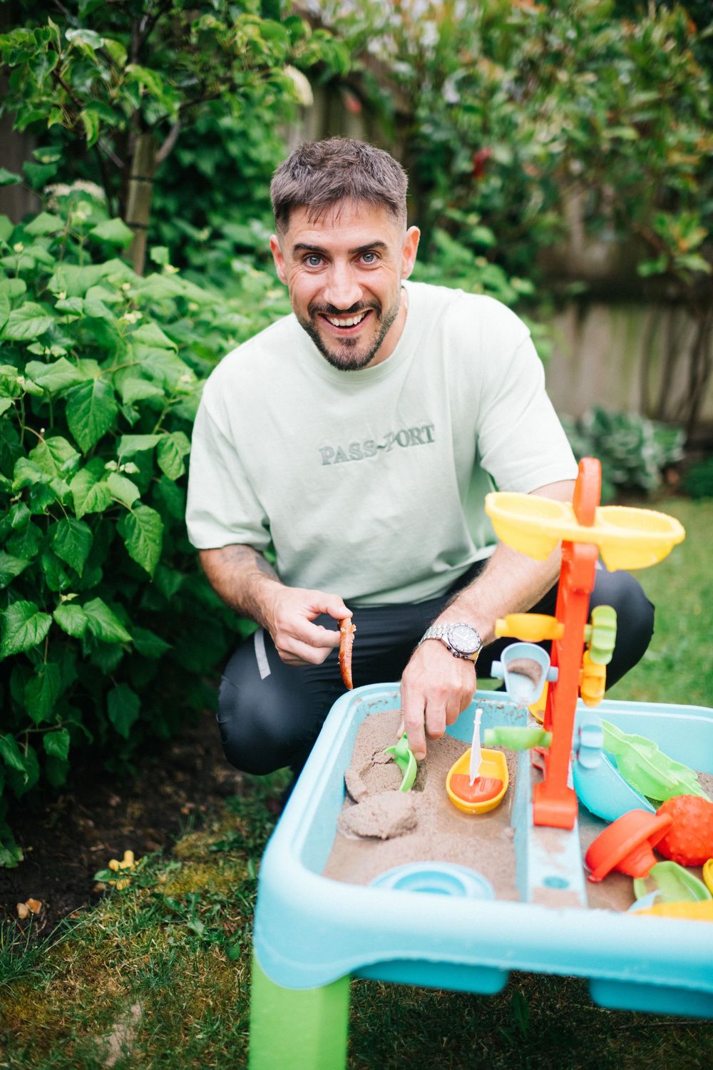 Someone playing with a colorful children's water table toy in a garden setting.