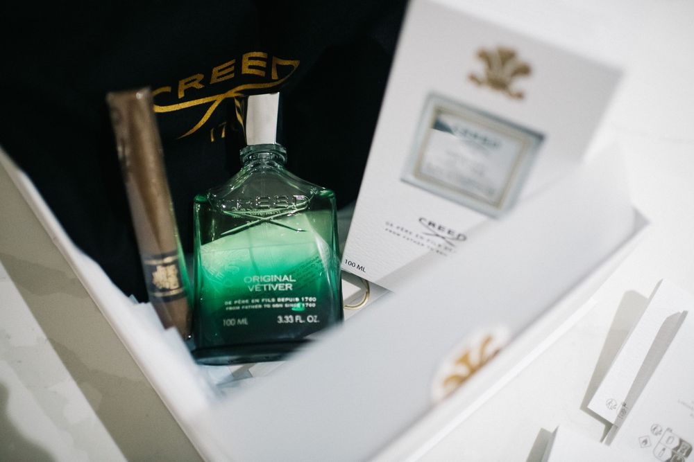 A green glass bottle of premium liquor displayed with wedding stationery.