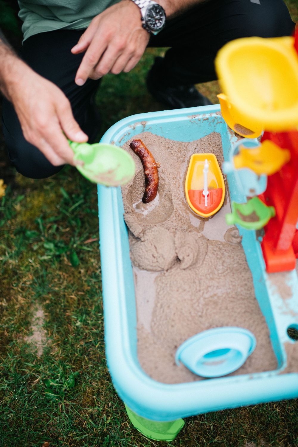 Close-up shots of hands playing with colorful sand toys and beach sand in blue container.