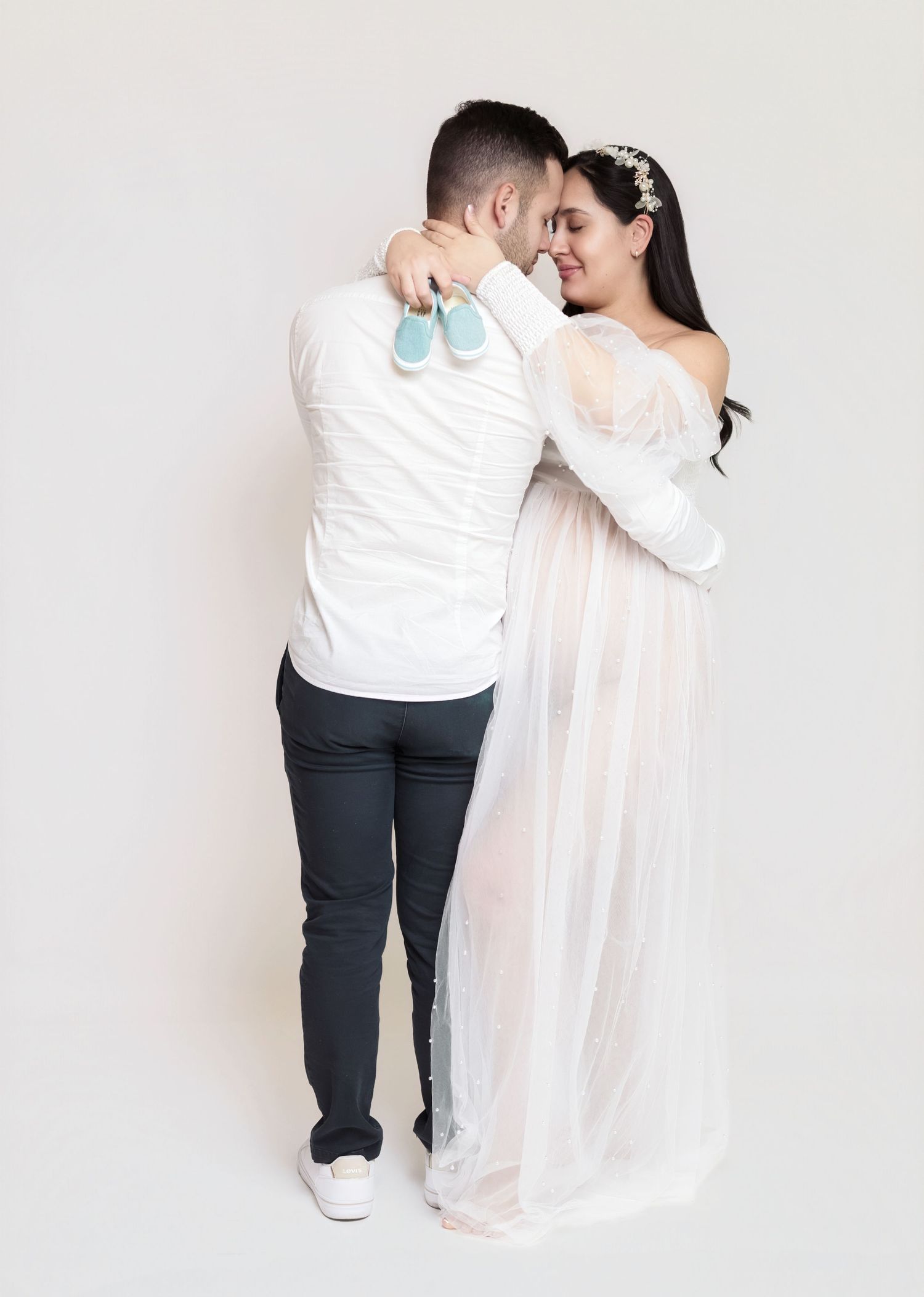 A couple in white and dark outfits shares a tender embrace in a minimalist photo series.