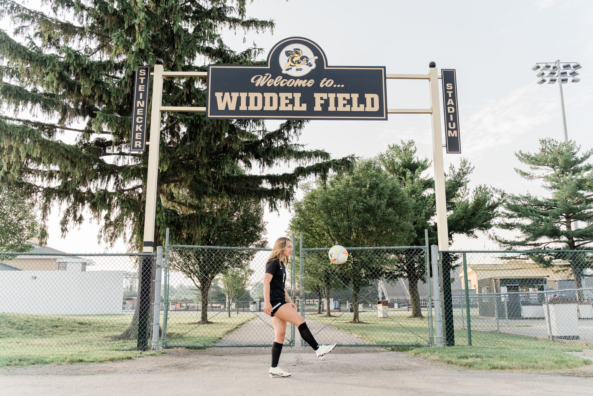 A series of five images showing a volleyball game and practice at Wilder Field with stadium lights and trees in the background.