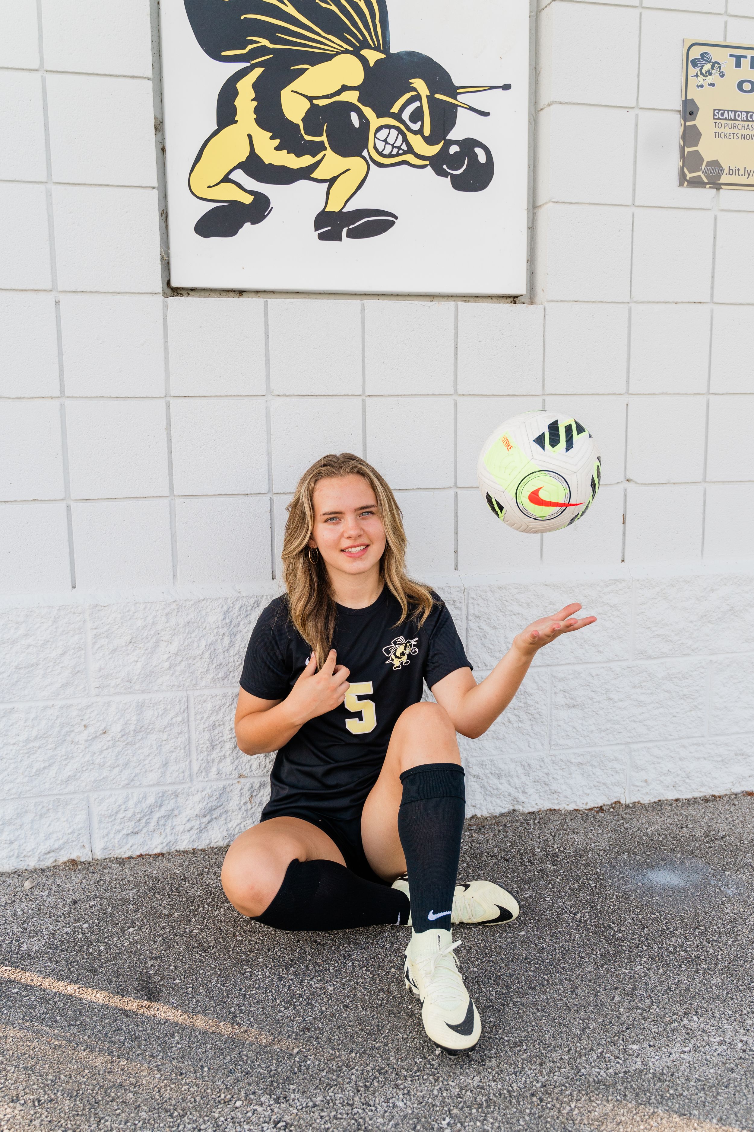 A sequence of four photos showing a person in a black uniform sitting and posing on pavement against a white wall.