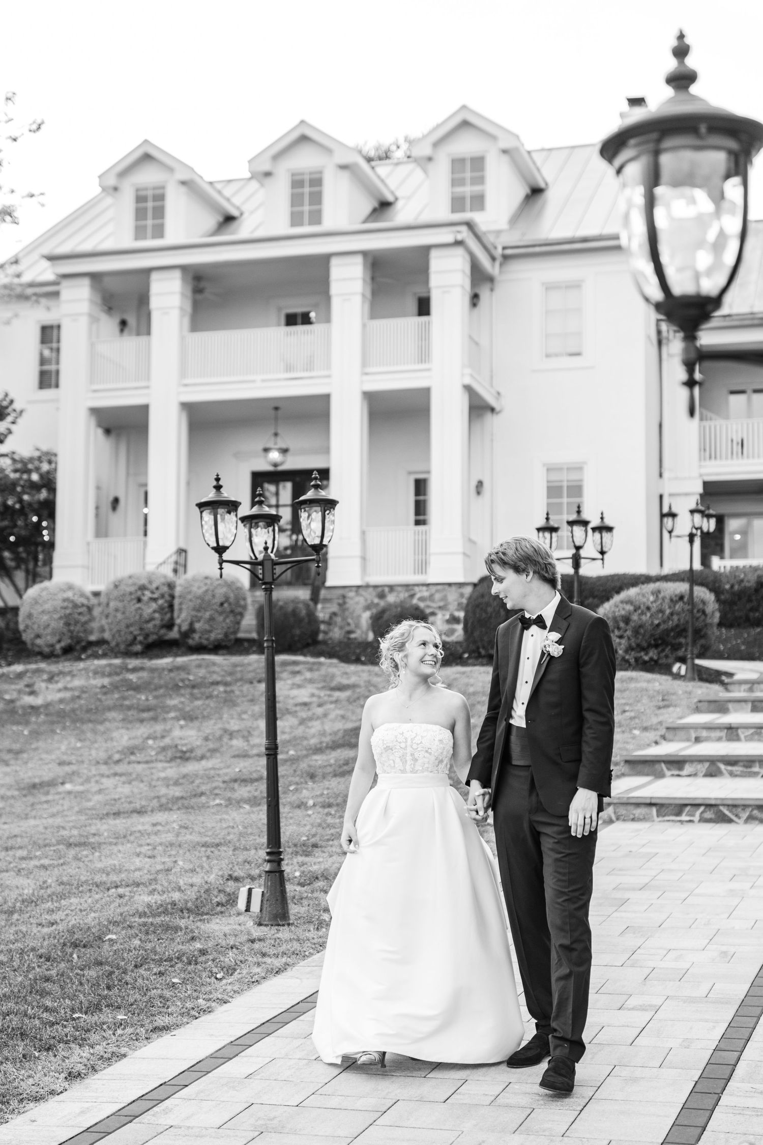 Classic black and white wedding photo in front of a stately southern mansion.