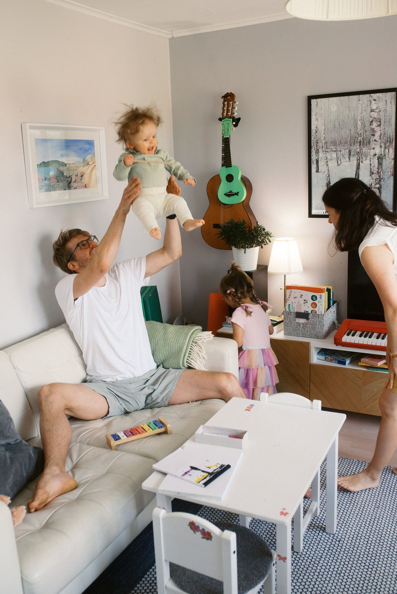 A sequence of photos shows someone jumping and dancing on a white couch with a green ukulele in a bright room.