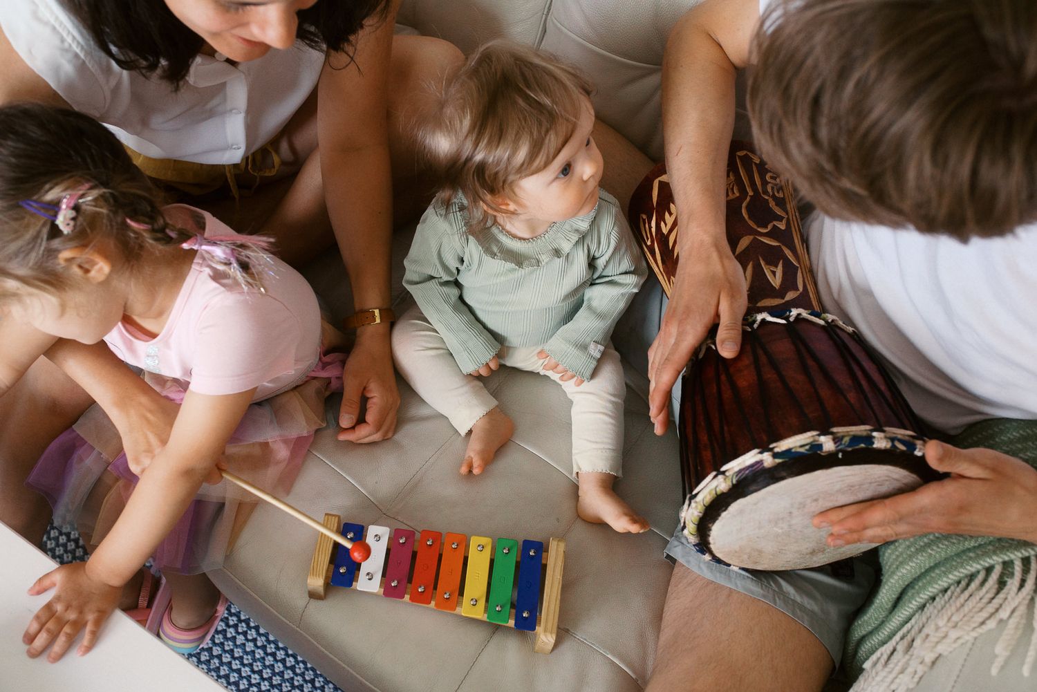 A person plays with a colorful xylophone toy while sitting on a carpeted floor.