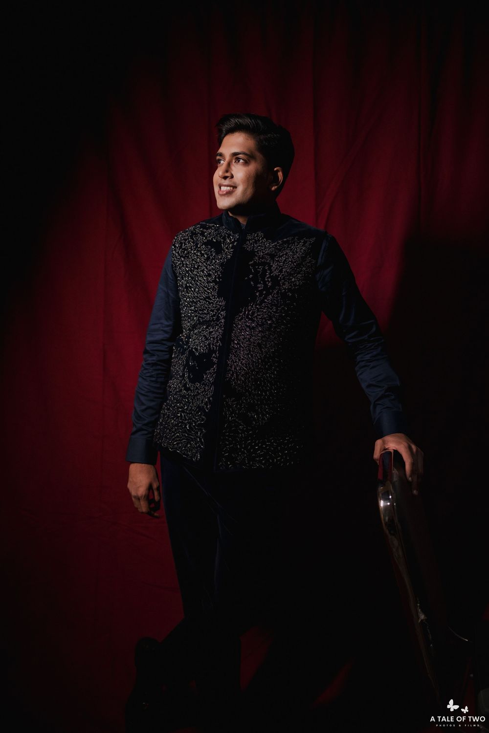 Person wearing a black textured coat and navy sleeves poses against a dramatic red backdrop in a creative portrait series.