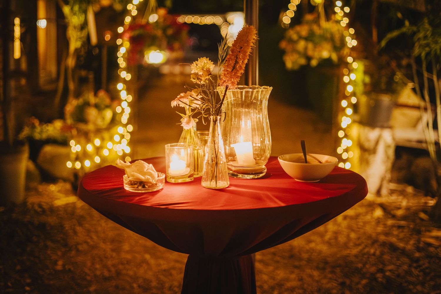 Candlelit table settings with string lights creating romantic ambiance.