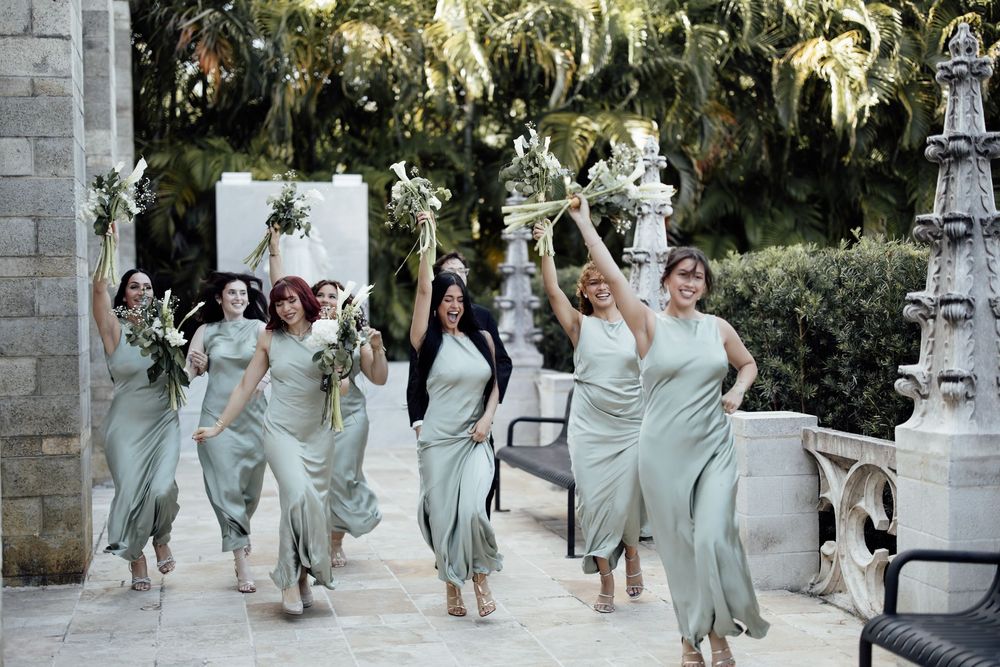 Bridesmaids in sage green dresses pose together for celebratory photos outdoors.